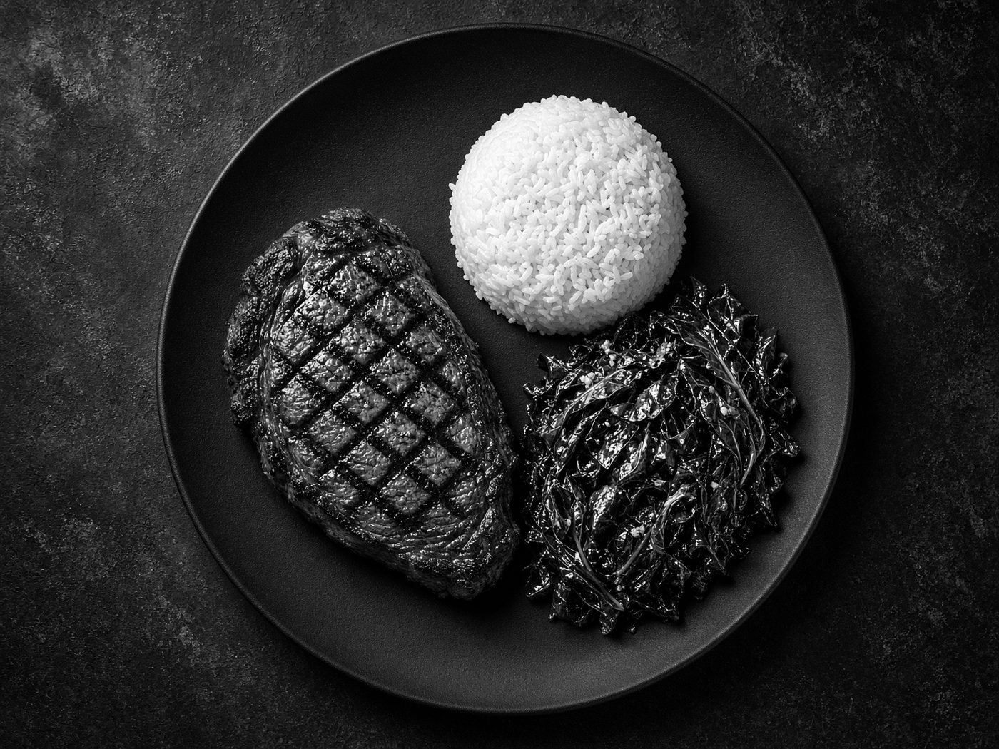 Black-and-white overhead of a precisely portioned meal on a dark plate.